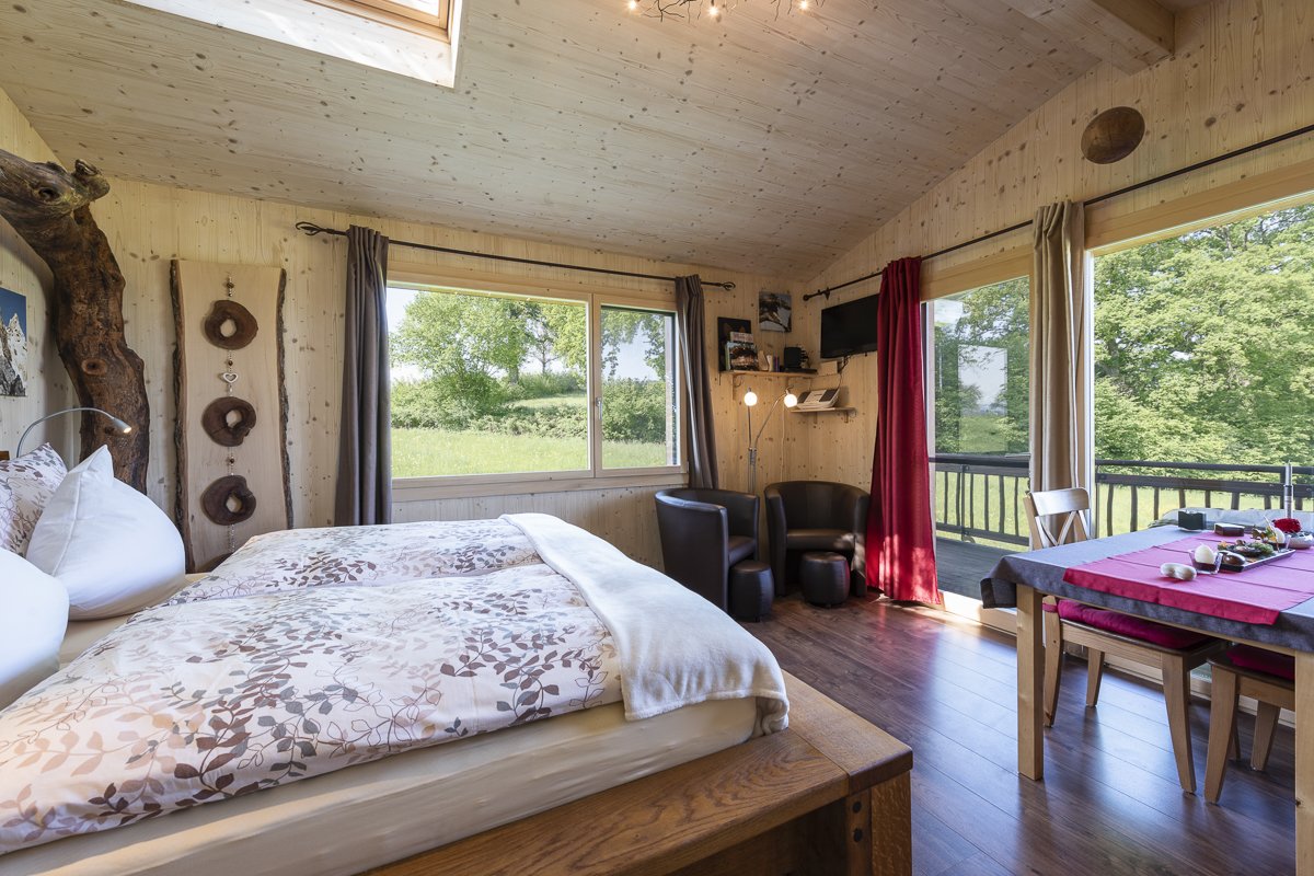 Wohnraum mit Bett und Esstisch im Wurzelbaumhaus in Neuenkirch